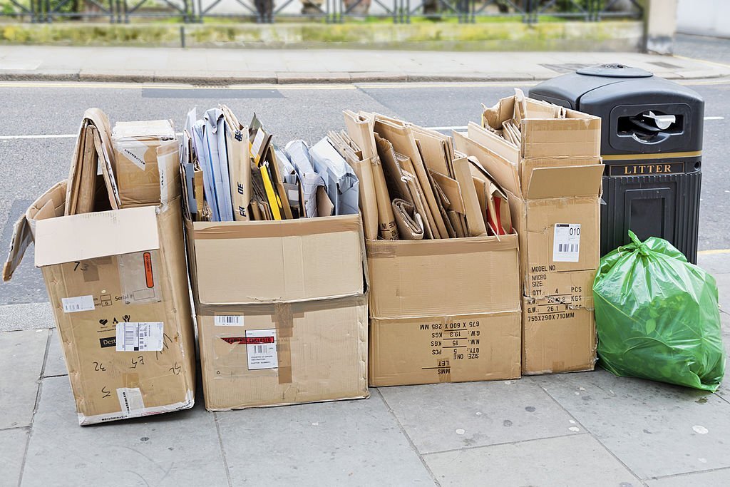 A neatly arranged stack of discarded cardboard boxes awaiting collection by refuse disposal crew on a street pavement in London.